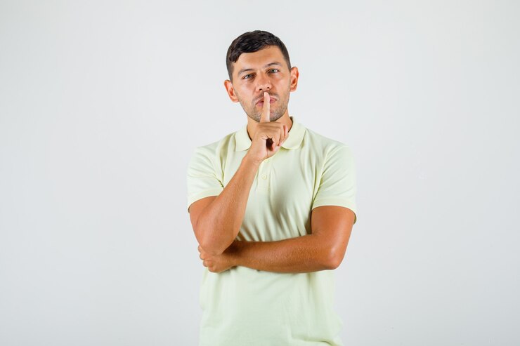 Foto grátis jovem colocando o dedo nos lábios em uma camiseta e parecendo na defensiva