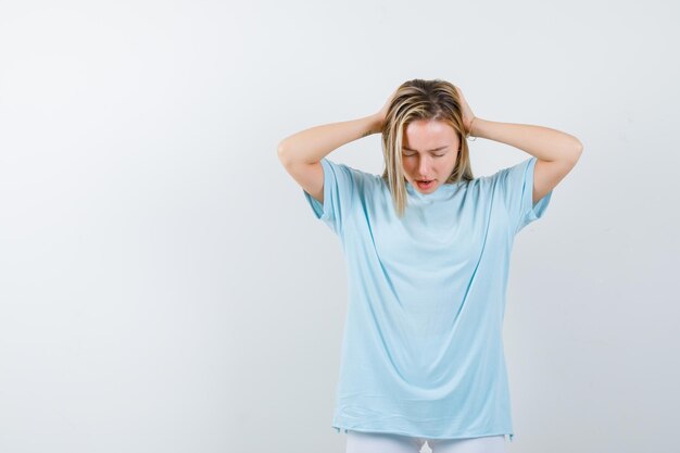 Jovem com as mãos na cabeça em uma camiseta e parecendo irritada isolada