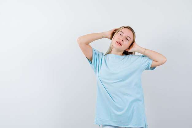 Jovem com as mãos na cabeça em uma camiseta e parecendo tranquila isolada