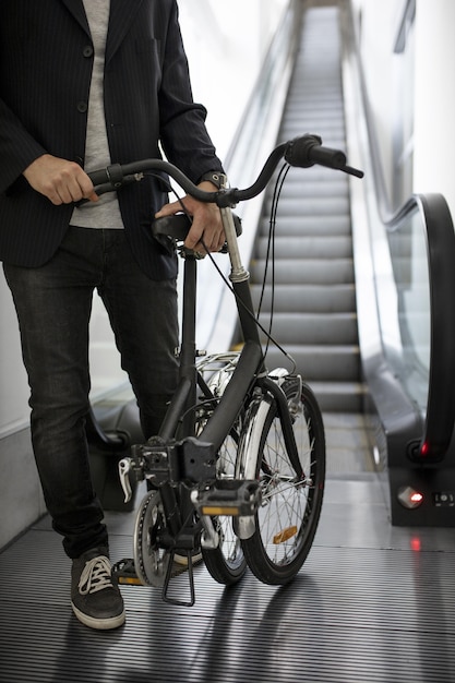 Jovem com bicicleta dobrável na escada rolante