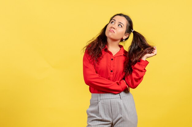 Jovem com blusa vermelha posando com rosto entediado em amarelo