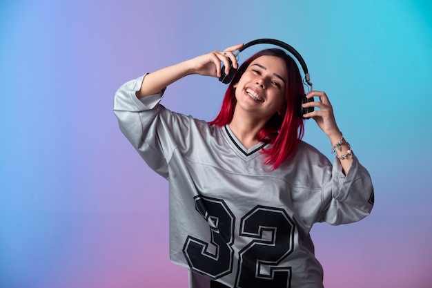Foto grátis jovem com cabelos rosa parece positiva e usando fones de ouvido.