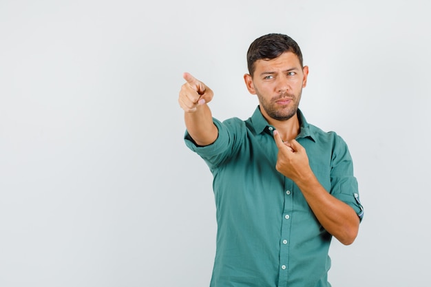 Foto grátis jovem com camisa mostrando algo e parecendo pensativo