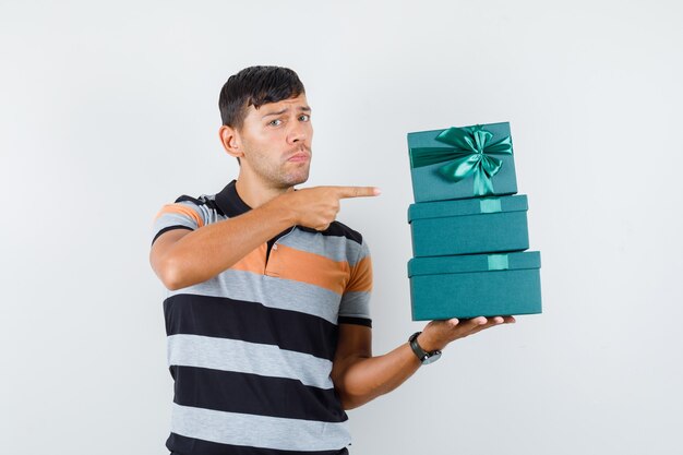 Jovem com camiseta apontando para caixas de presentes