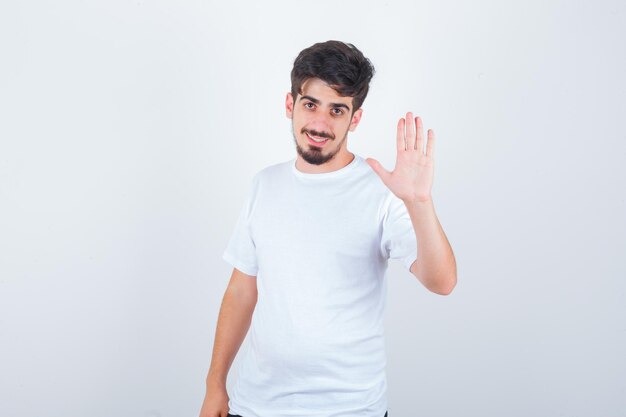 Jovem com camiseta, mostrando a palma da mão e parecendo fofo