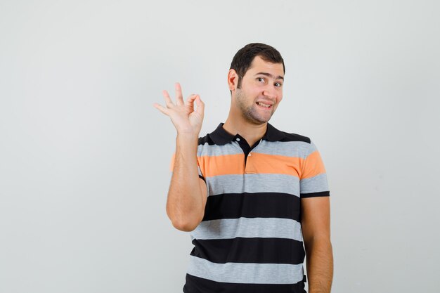 Jovem com camiseta mostrando gesto de ok e parecendo satisfeito