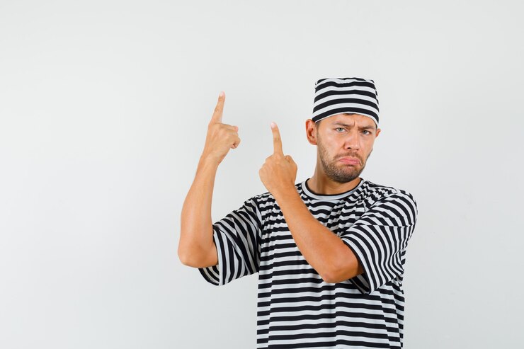 Foto grátis jovem com chapéu de camiseta listrada apontando para cima e parecendo abatido