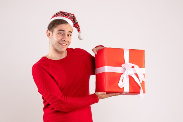 Jovem com chapéu de papai noel segurando uma caixa vermelha de presente em fundo branco