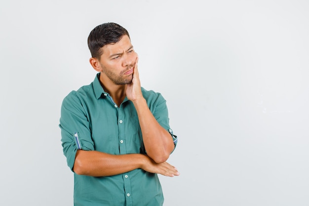 Jovem com dor de dente na camisa e parecendo triste