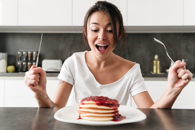 Jovem com fome, sentado na cozinha em casa