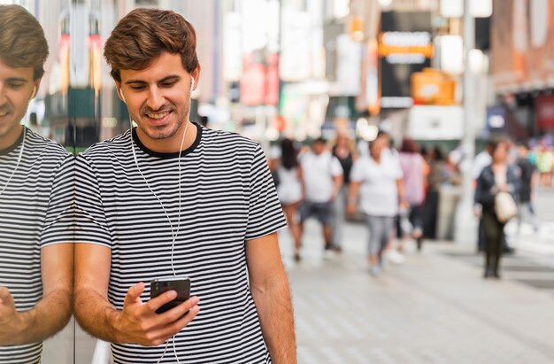 Jovem com fones de ouvido descansando por uma parede de vidro