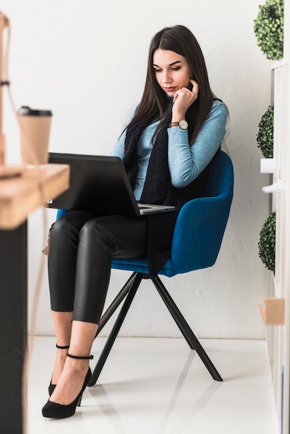 Jovem com laptop na cadeira