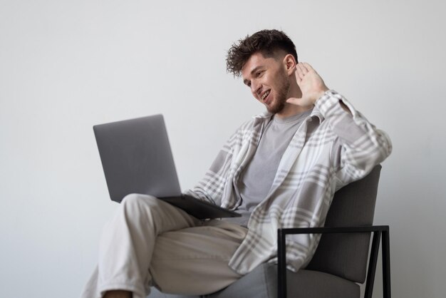 Jovem com laptop relaxando na cadeira isolada no fundo branco