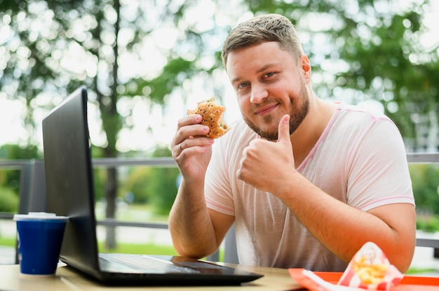 Jovem com laptop sorrindo para a câmera