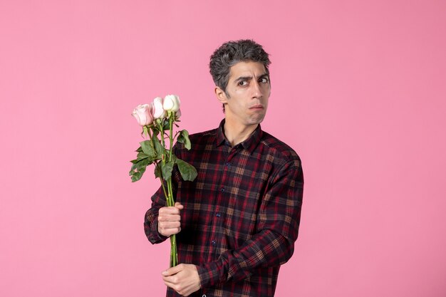 Jovem com lindas rosas cor de rosa na parede cor de rosa