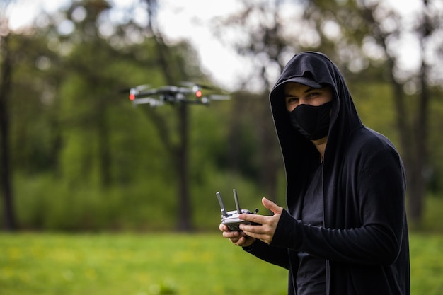 Jovem com máscara usa controle remoto para drone na floresta