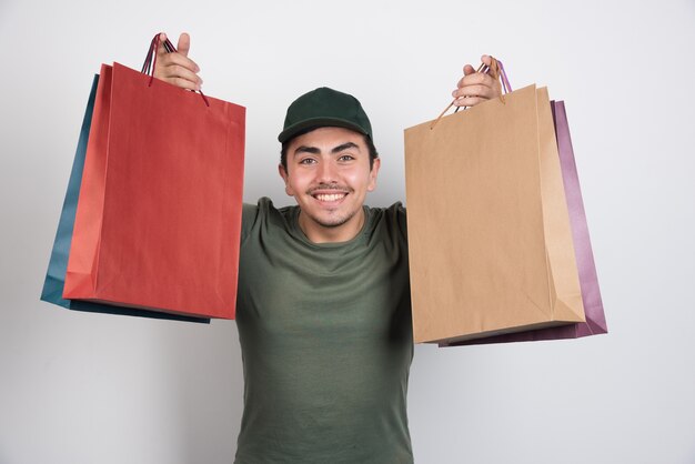 Jovem com sacolas de compras em fundo branco.