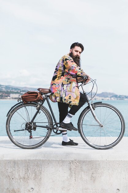 Foto grátis jovem com sua bicicleta no quebra-mar perto da costa