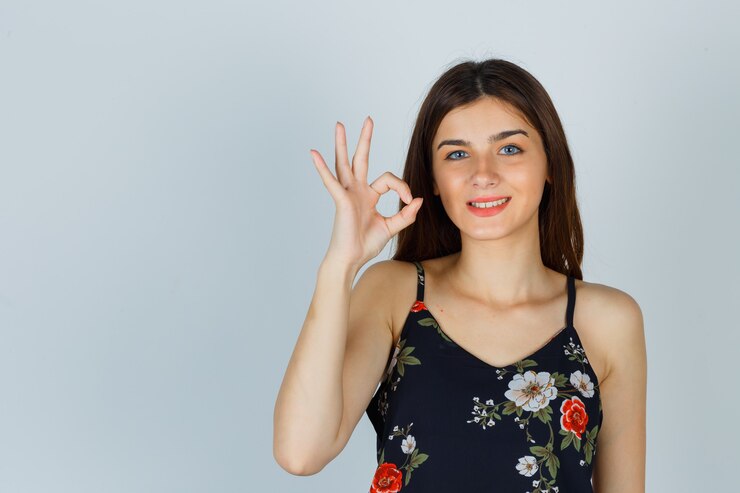 Foto grátis jovem com top floral mostrando um gesto de ok e parecendo feliz