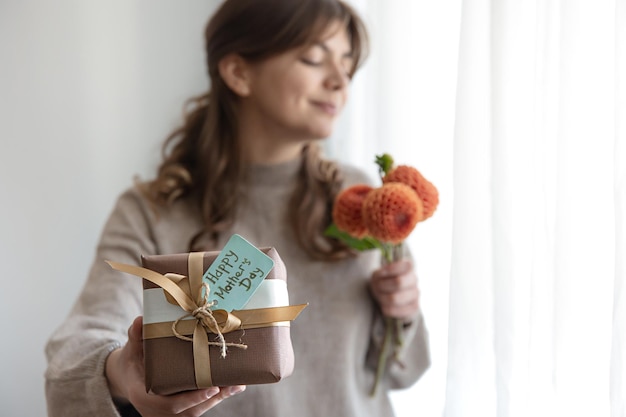 Jovem com um presente para o dia das mães e um buquê de flores nas mãos