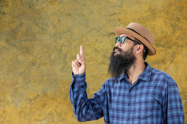 Jovem com uma barba longa, vestindo um chapéu e óculos