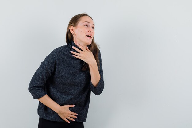 Jovem com uma camisa de mãos dadas no pescoço e na barriga e parecendo feliz