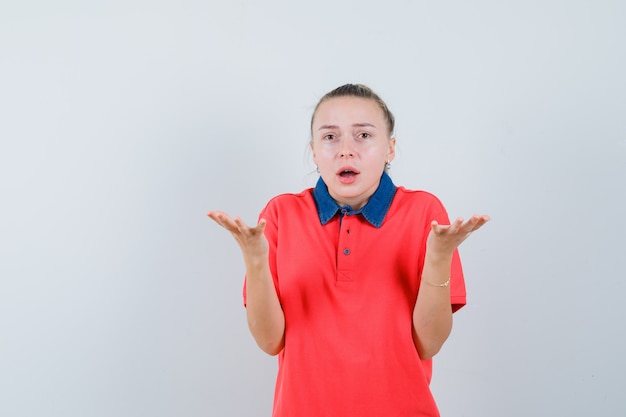 Jovem com uma camiseta levantando as mãos em um gesto perplexo