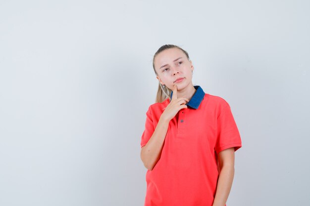 Jovem com uma camiseta olhando para longe e pensativa