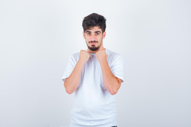 Jovem com uma camiseta segurando os punhos no peito e parecendo confiante