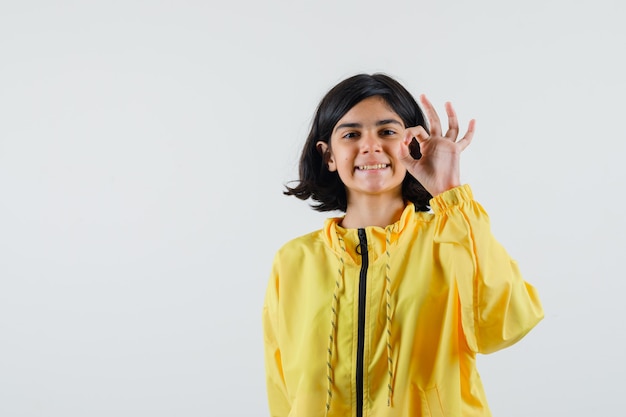 Jovem com uma jaqueta amarela mostrando sinal de ok e parecendo feliz