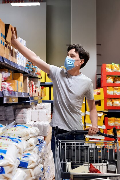 Jovem com uma máscara facial olhando lanches em um supermercado