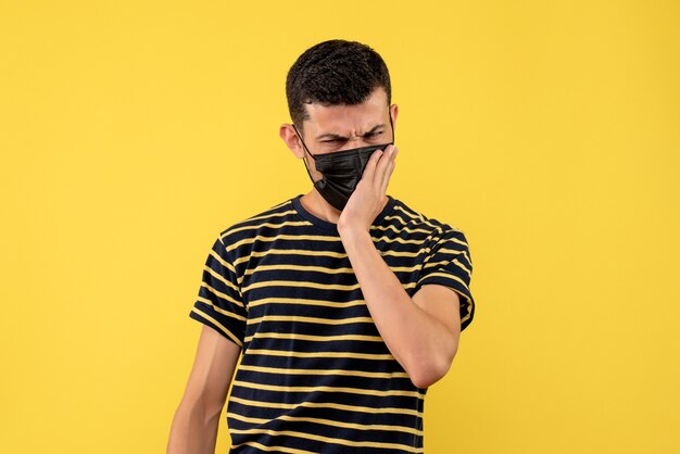 Jovem com vista frontal em uma camiseta listrada em preto e branco com fundo amarelo