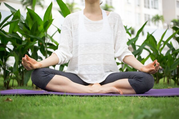 Jovem concentrada praticando yoga no gramado