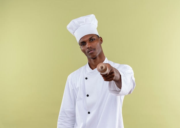 Jovem confiante afro-americana com uniforme de chef segurando o pino isolado em um fundo verde com espaço de cópia