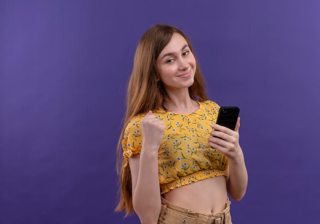 Jovem confiante segurando um telefone celular com o punho cerrado em um espaço roxo isolado com espaço de cópia