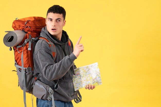 Jovem confuso de frente com uma mochila vermelha segurando um mapa