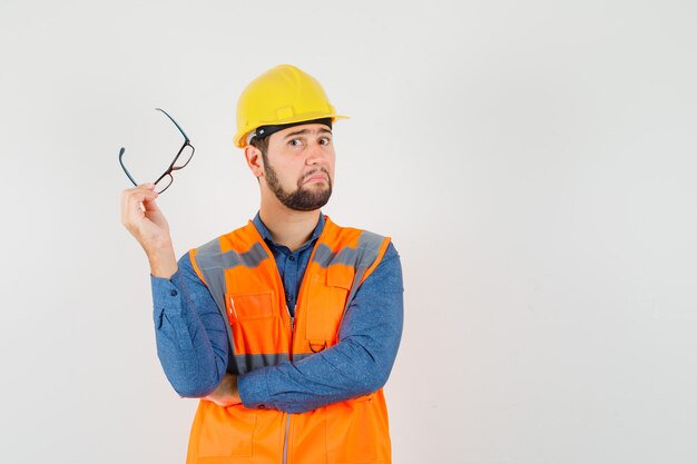 Jovem construtor segurando óculos na camisa