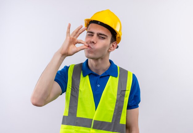 Foto grátis jovem construtor usando uniforme de construção e capacete de segurança gosta