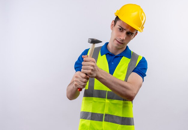 Jovem construtor usando uniforme de construção e martelos de capacete de segurança