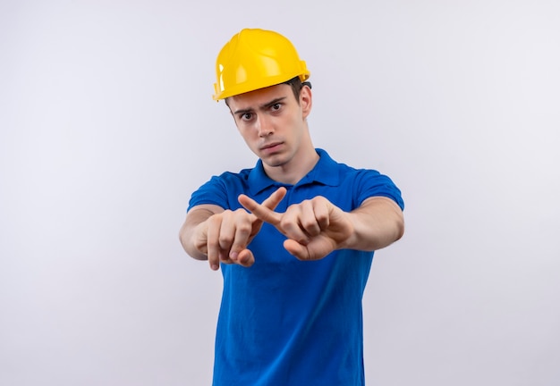 Jovem construtor vestindo uniforme de construção e capacete de segurança cruzando os indicadores