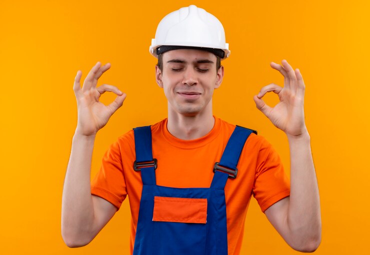 Foto grátis jovem construtor vestindo uniforme de construção e capacete de segurança, fechando os olhos e passando bem com as mãos