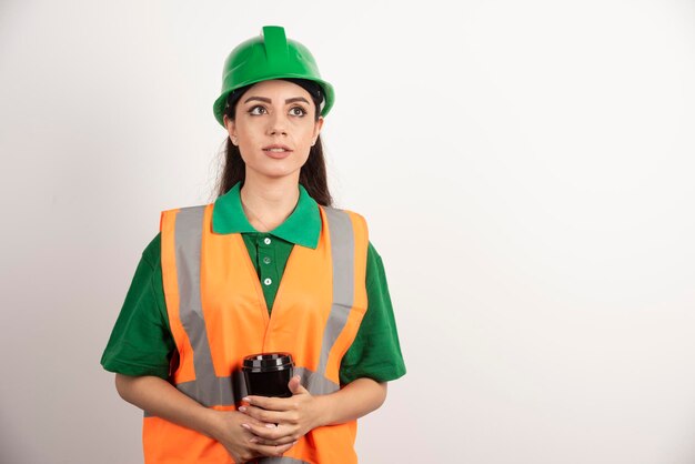 Jovem construtora segurando o copo preto e desviar o olhar. foto de alta qualidade