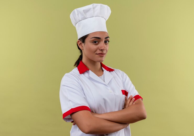 Foto grátis jovem cozinheira caucasiana confiante com uniforme de chef cruzando os braços isolados na parede verde com espaço de cópia