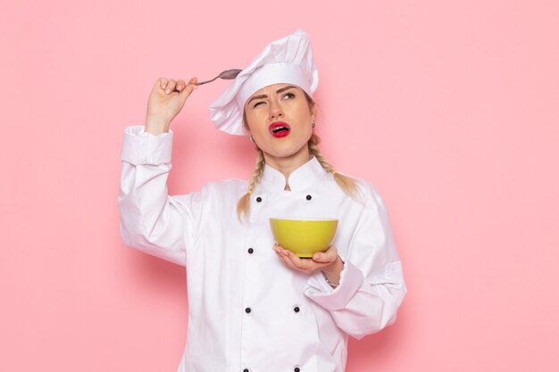 Jovem cozinheira de terno branco segurando uma placa verde e pensando na cozinheira do espaço rosa