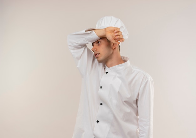 Jovem cozinheiro cansado vestindo uniforme de chef colocando o pulso na testa com espaço de cópia