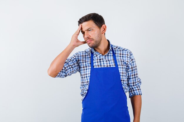 Jovem cozinheiro com um avental azul e uma camisa