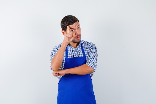 Foto grátis jovem cozinheiro com um avental azul e uma camisa