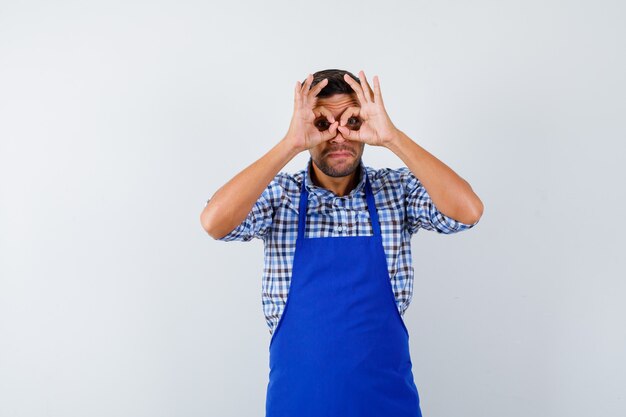 Jovem cozinheiro com um avental azul e uma camisa