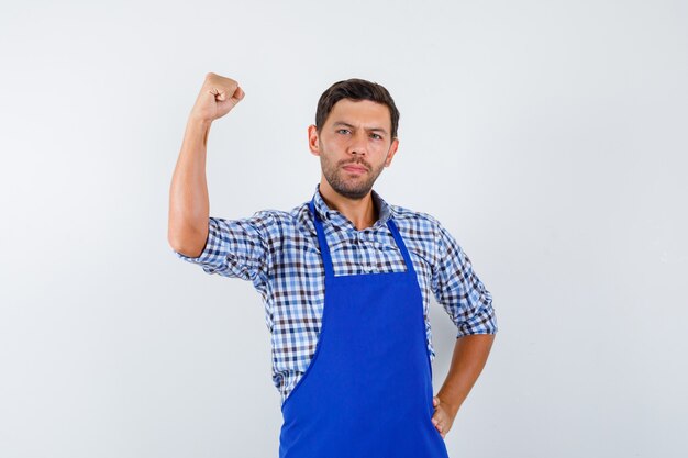 Jovem cozinheiro com um avental azul e uma camisa