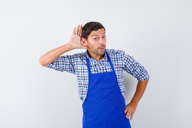 Jovem cozinheiro com um avental azul e uma camisa